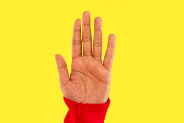 Hand raised against a vivid yellow background, symbolizing communication and connection in an expressive moment