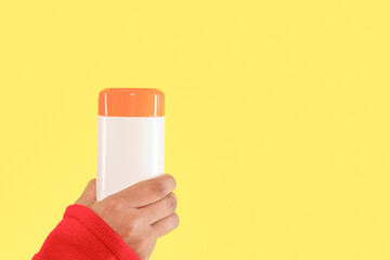 Brightly colored container held against a vibrant yellow background in a playful indoor setting...