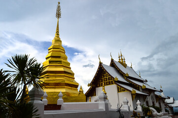 Fototapeta premium Church and Golden Pagoda, Lanna Architecture at Wat Phra That Pu Chae, symbols of Buddhism, South East Asia at Phrae Northern Thailand