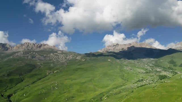 Mountains with fresh green grass in summer. Clouds over the mountains at sunny day. Summer landscape. Digor Gorge in North Ossetia, Caucasus, Russia.
