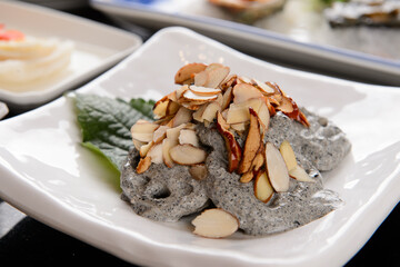 Dressing is poured over lotus root salad and almond slices are sprinkled on top.
