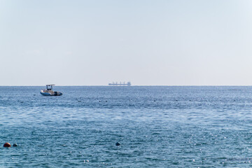 Obraz premium Calm blue sea with the silhouette of a large ship on the horizon