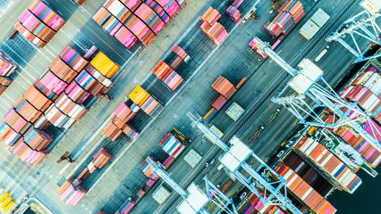 A straight-down aerial photo of shipping cranes operating over a dock filled with colorful cargo containers. The image highlights the symmetry and industrial activity of a modern shipping port.