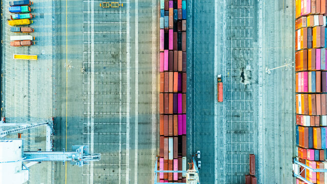 Top-down aerial photo of a container yard showing neatly arranged cargo containers, internal roads, and loading equipment. The image emphasizes the structured nature of global logistics systems.