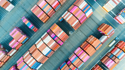Aerial top view of organized stacks of colorful shipping containers at a busy cargo yard. The image reflects the logistics efficiency and volume of global trade through maritime transport.