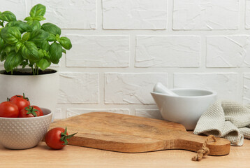 Kitchen utensils, fresh tomatoes, basil plant and mortar with pestle on wooden table