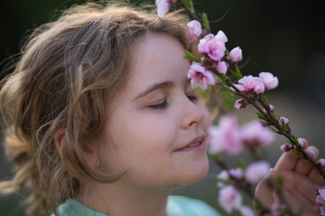 Naklejka premium Spring child portrait. Kid in a blooming meadow. Childhood joy in nature. Child with flowers on spring day. Smiling child playing outdoors in spring nature. Dreamy spring.