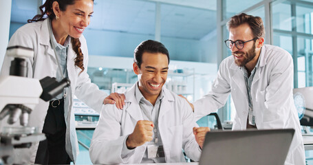 Laptop, celebration and team of scientists in laboratory for medical research success for...