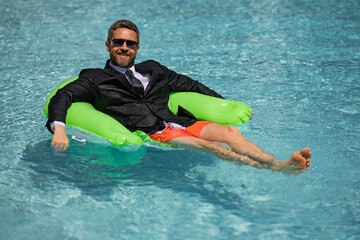 Crazy Business man in suit wit laptop in swimming pool. Crazy summer freelancer working in pool. Funny businessman with laptop on sea beach. Summer travel and beach. Creative online strategy.
