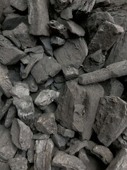Close up view of pieces of black charcoal. Charcoal is produced by strongly heating wood in minimal oxygen to remove all water and volatile constituents. Full frame of charcoal background.