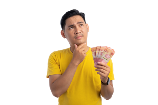 Pensive young Asian man touching his chin, holding money, looking up with doubtful expression isolated on transparent background