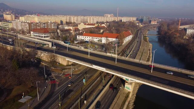 High angle drone overview of Budapest highway and bridge as cars move in golden hour city glow