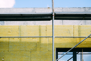 Mineral wool house insulation. Construction site with scaffolding and high-density slab insulation...