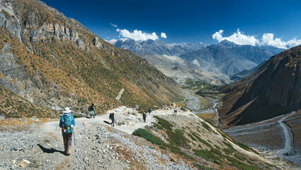 Panoramic view of mountains with group hikers on trail against background of picturesque mountain landscape while trekking around Annapurna in Himalayas, Nepal.