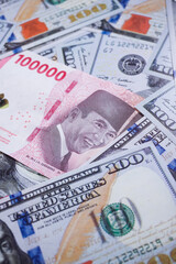 background of piles of US dollar banknotes overlapping Indonesian rupiah banknotes. illustration of inflation of the US dollar currency against the Indonesian rupiah currency