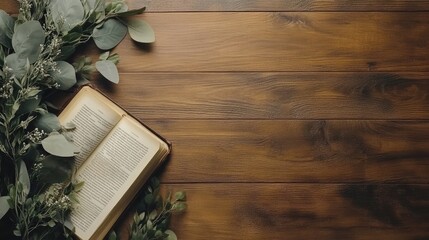 Open book with greenery on wooden table