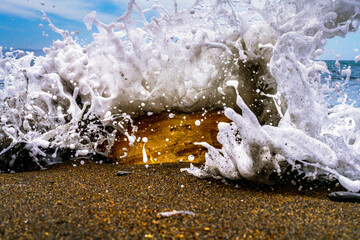 Dramatic seafoam wave crashing over shoreline rock