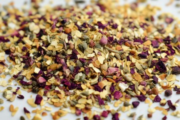 Colorful blend of dried herbs and flowers scattered on a white surface, perfect for culinary use