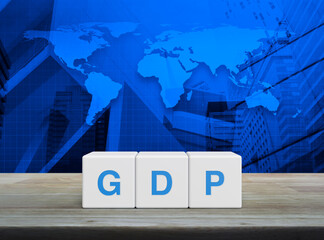 GDP acronym on white block cubes on wooden table over world map, office city tower and skyscraper, Gross domestic product concept, Elements of this image furnished by NASA