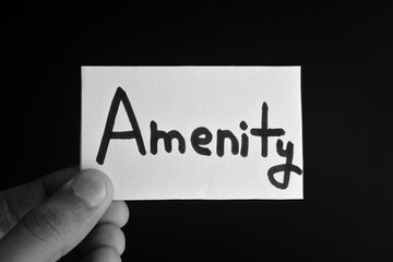 Hand holding a paper card with the word AMENITY
