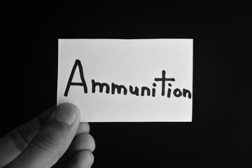 Hand holding a paper card with the word AMMUNITION