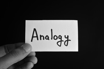 Hand holding a paper card with the word ANALOGY