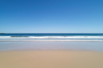 Tranquil ocean waves on a serene sandy beach under clear blue skies