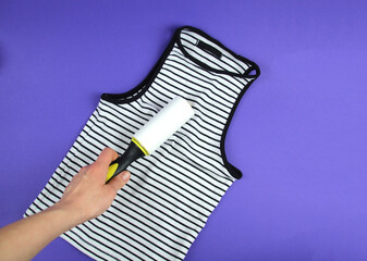 Woman's hand using a clothes roller to keep her T-shirt clean