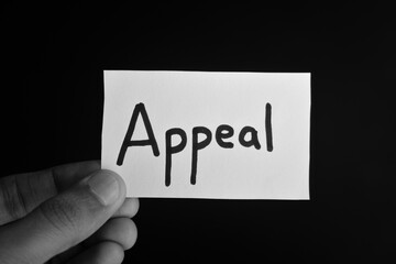 Hand holding a paper card with the word APPEAL
