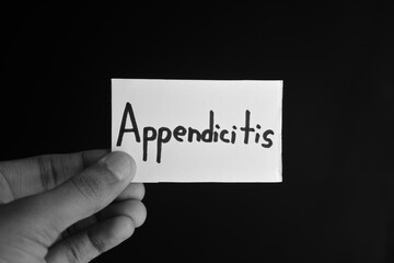 Hand holding a paper card with the word APPENDICITIS