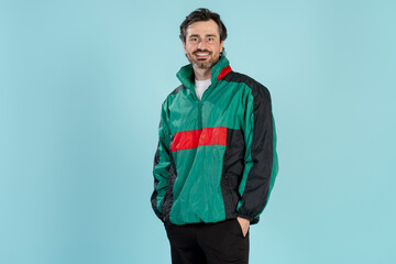 Smiling man wearing retro 90s style jacket posing on blue background