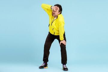 Tired sportsman wiping sweat after training on blue background