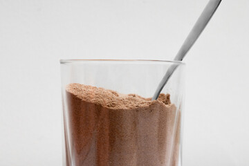 Closeup of cocoa powder and cinnamon in a bowl with a glass of cocoa powder creating a delicious sweet dessert scene