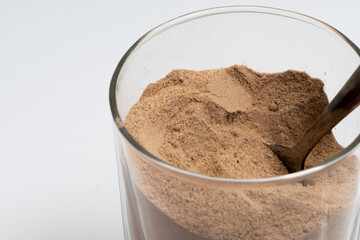 Closeup of cocoa powder and cinnamon in a bowl with a glass of cocoa powder creating a delicious sweet dessert scene