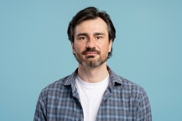 Obraz premium Portrait of confident middle-aged man with grey hair and beard on blue background