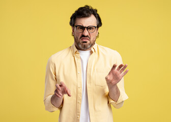 Disgusted man gesturing stop sign with hands on yellow background