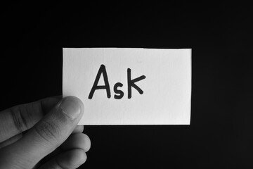 Hand holding a paper card with the word ASK