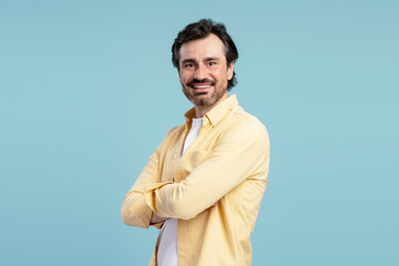 Smiling confident businessman crossing arms on blue background