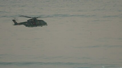Military helicopter flying low over water surface