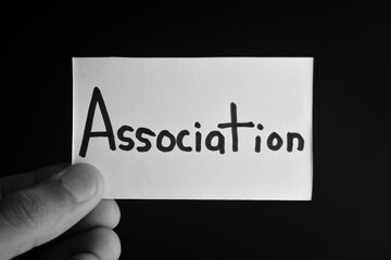 Hand holding a paper card with the word ASSOCIATION