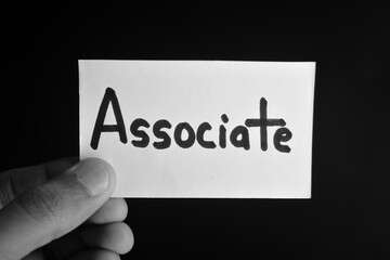 Hand holding a paper card with the word ASSOCIATE