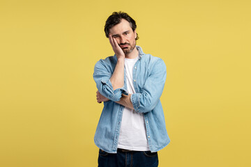 Bored man leaning head on hand on yellow background