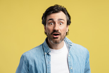 Shocked man opening mouth showing surprise on yellow background