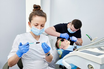 Dentist and Assistant Cementing Crown. Installing a dental crown. Teamwork in Dentistry.