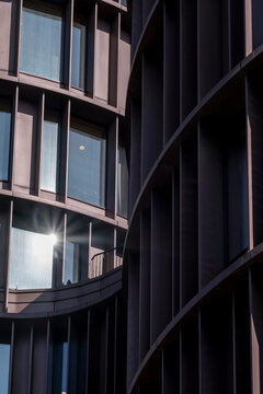 Curved metal and glass surface of modern structure with subtle reflections and vertical composition