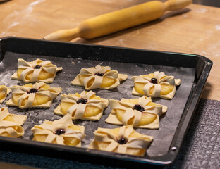 Puff pastry with pineapple wedges wrapped and cherry on top, on the baking tray in the kitchen counter top. Baking