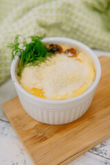 Indulge in a delectable baked dish topped with fresh dill and cheese, captured in a relaxing setting with soft textiles adding exquisite charm to the presentation.