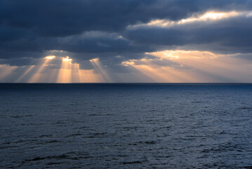 Slanting rays of the sun in the storm clouds over the ocean