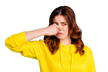 Photo of disgusted girl smelling something bad nasty looking shutting her nose isolated over vivid...