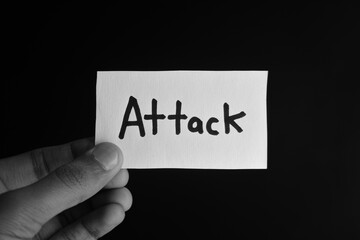 Hand holding a paper card with the word ATTACK